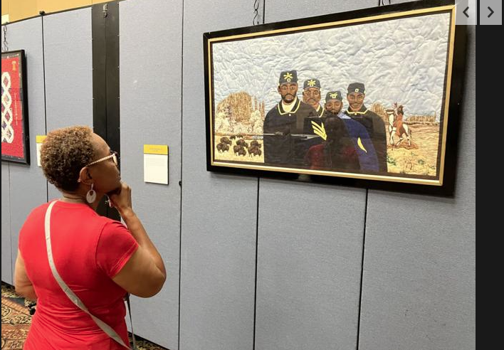 A visitor admires a quilt depicting the Buffalo Soldiers.