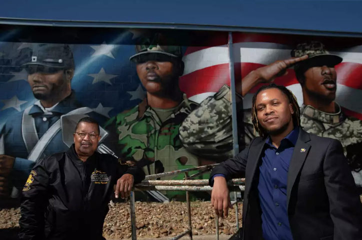 Captain Matthews and Desmond Bertrand-Pitts in front of a mural at BSNM